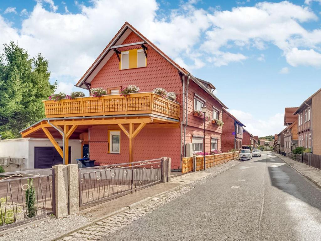 ein rotes Haus mit Balkon auf einer Straße in der Unterkunft Flat in Ilsenburger Harz near the ski area in Ilsenburg