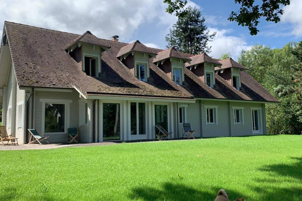una casa con techo de gambrel con un gran patio en Gîte des Etangs, en Glanville