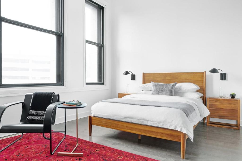 a bedroom with a bed and a chair and windows at Abode Pittsburgh - Downtown Convention Center in Pittsburgh