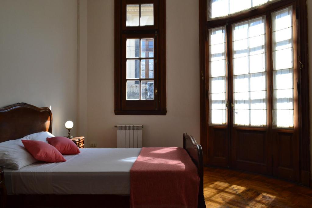 a bedroom with a bed and two windows at Che Argentina Hostel Suites in Buenos Aires