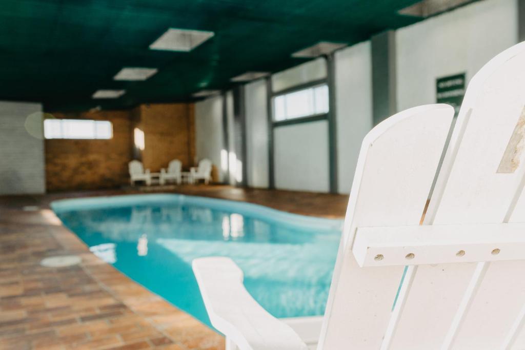 a pool with white chairs next to a swimming pool at Deer Park Motor Inn Armidale in Armidale