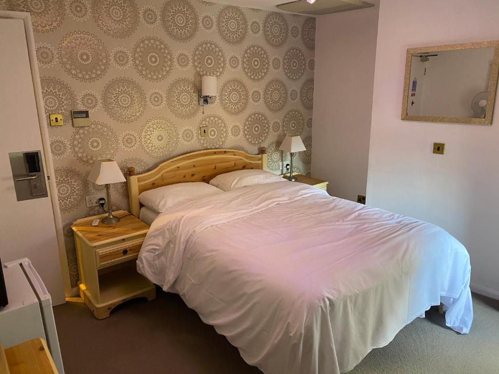 um quarto com uma grande cama branca e um espelho em Three Queens Hotel em Burton upon Trent