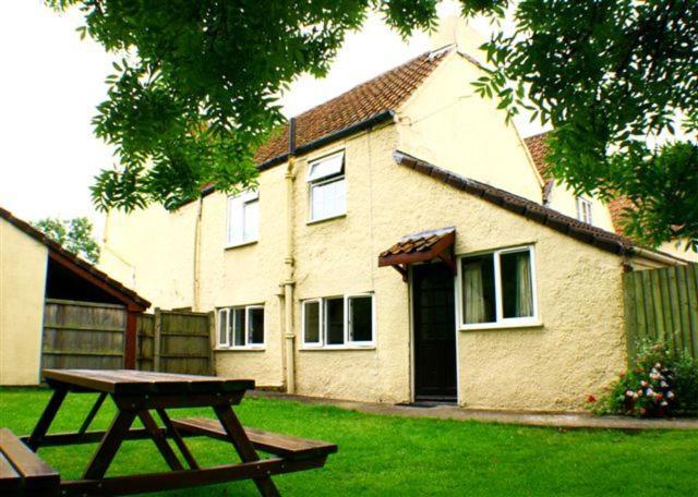 una casa con una mesa de picnic delante de ella en Doubleton Farm Cottages, en Weston-super-Mare