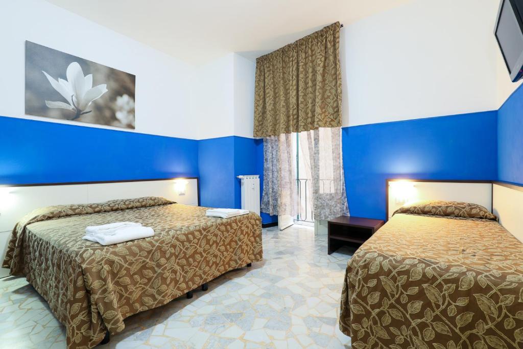 Habitación de hotel con 2 camas y paredes azules en Mini Hotel en Génova