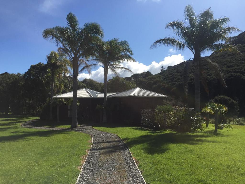 une maison avec des palmiers dans une cour dans l'établissement The Bungalow, sur l’île de la Grande Barrière