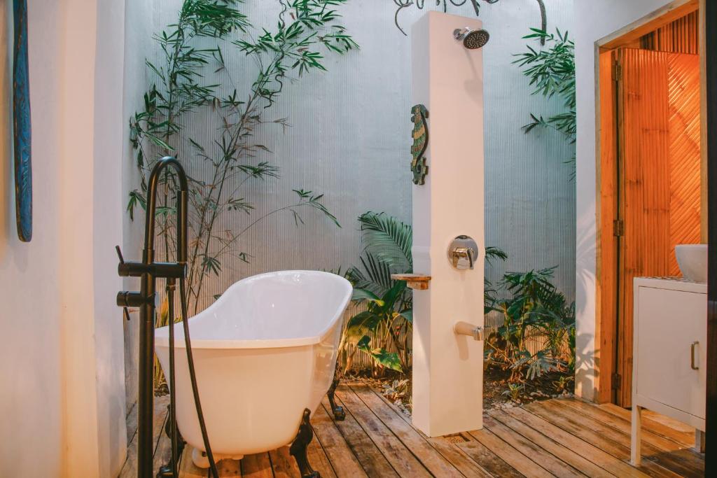 SANSE Boutique Hotel في إل نيدو: حوض استحمام في الحمام والنباتات على الحائط