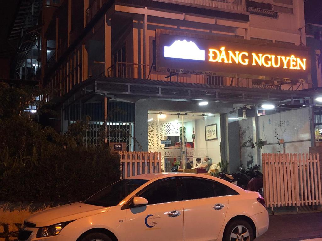 un coche blanco estacionado frente a un edificio por la noche en Dang Nguyen Guesthouse, en Da Lat