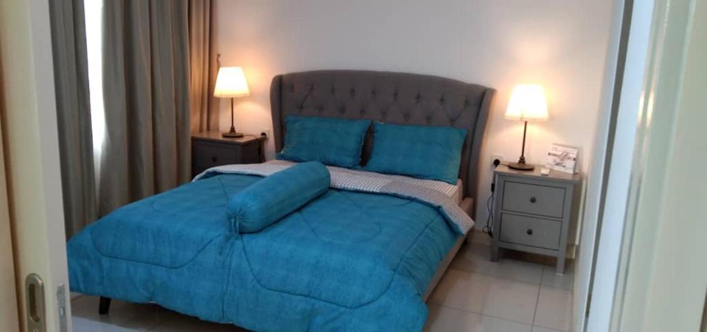 ein Schlafzimmer mit einem blauen Bett und zwei Nachttischen in der Unterkunft PINTARMAN SUITES @ MIRI TIMES SQUARE in Miri
