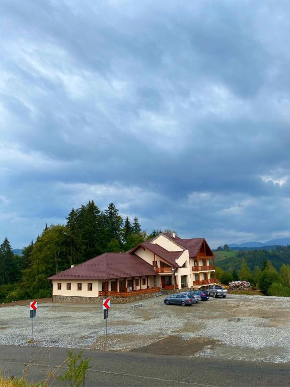 a large building with cars parked in a parking lot at PENSIUNEA BRADUL in Dealu Ştefăniţei