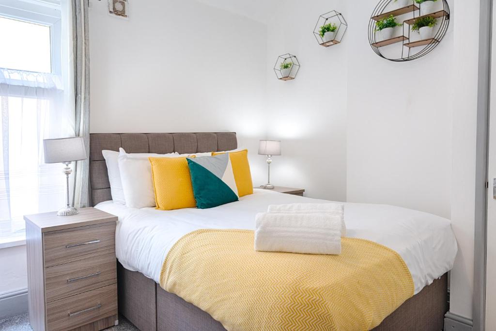 a bedroom with a bed with a yellow blanket on it at STOP! Stay at The Jersey in Swansea