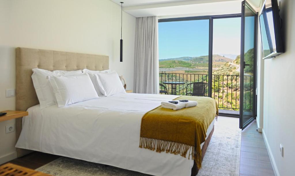 a bedroom with a large bed and a balcony at DouroXisto in Peso da Régua