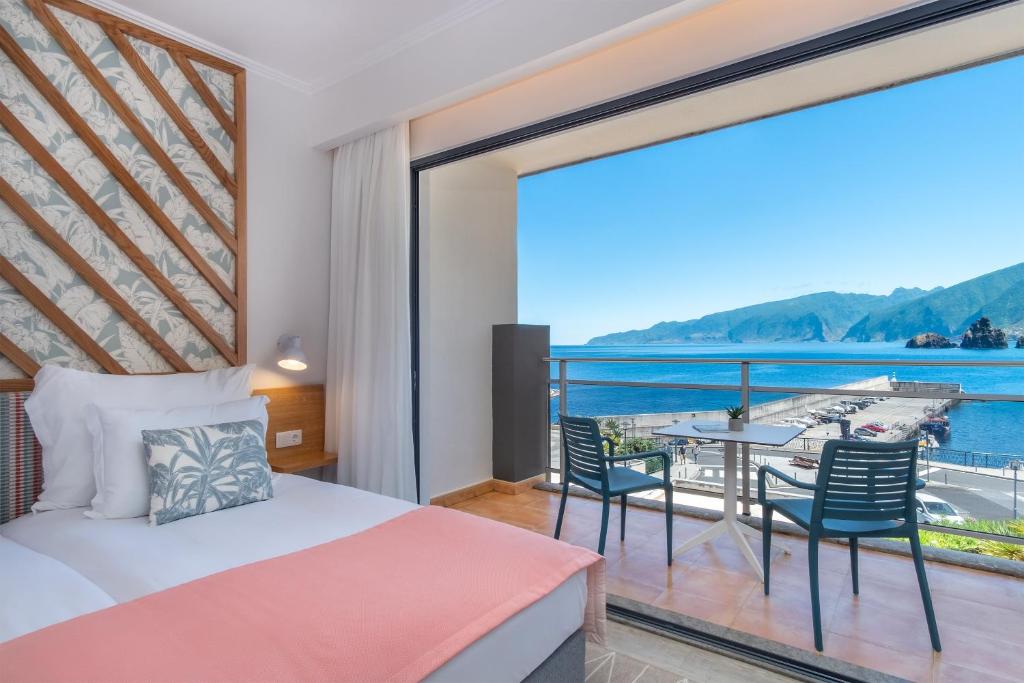 a bedroom with a bed and a balcony with a view at Aqua Natura Bay in Porto Moniz