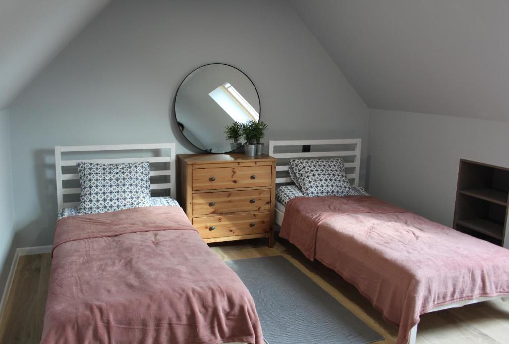 a bedroom with two beds and a mirror and a dresser at Agroturystyka Pokoje Stajnia Lidia in Serock