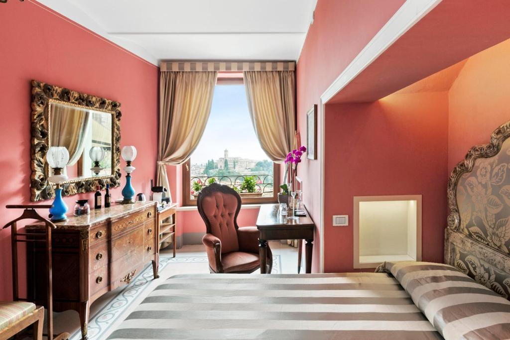 a bedroom with red walls and a desk and a bed at Residenza d'Epoca Palazzo Borghesi in Siena