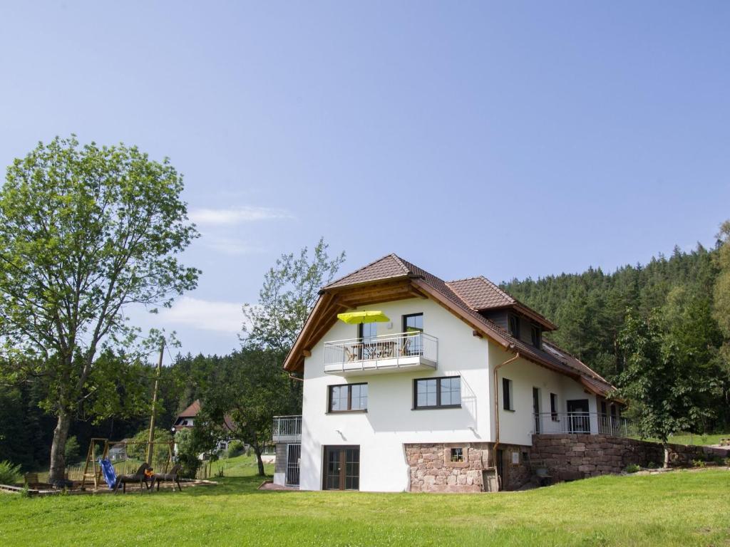 a white house with a balcony on a grass field at WaldFrieder Ferienwohnungen in Lauterbach