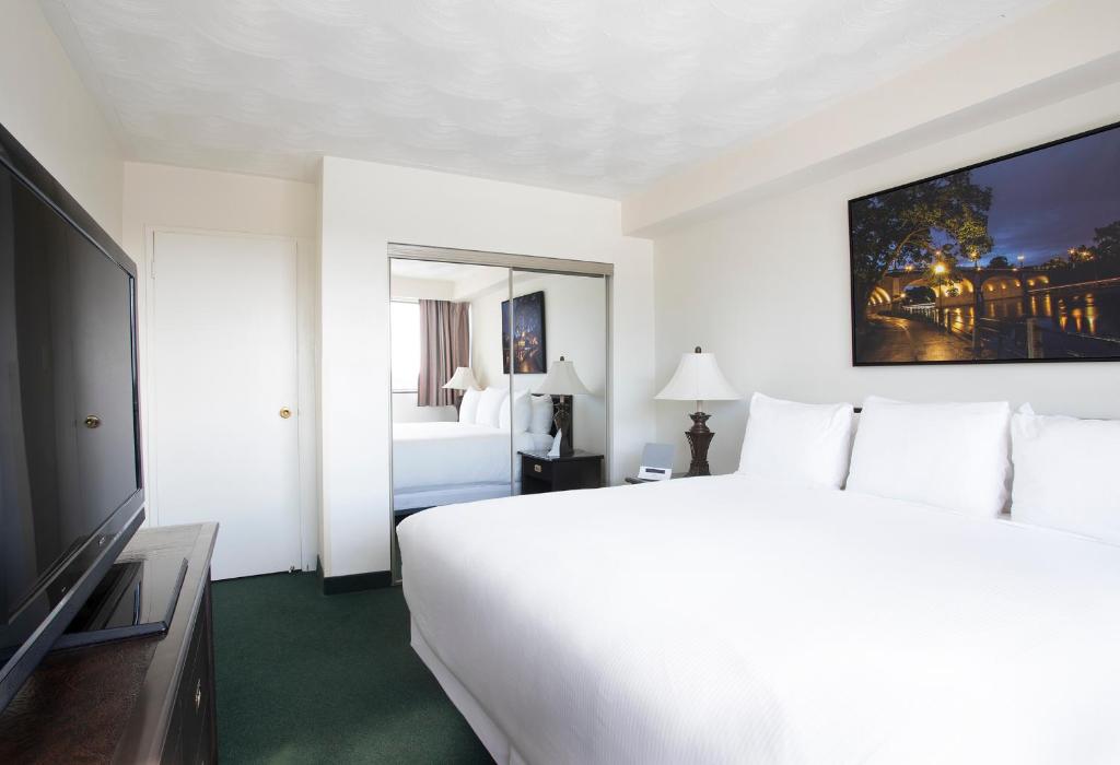 a hotel room with a large white bed and a television at The Business Inn in Ottawa