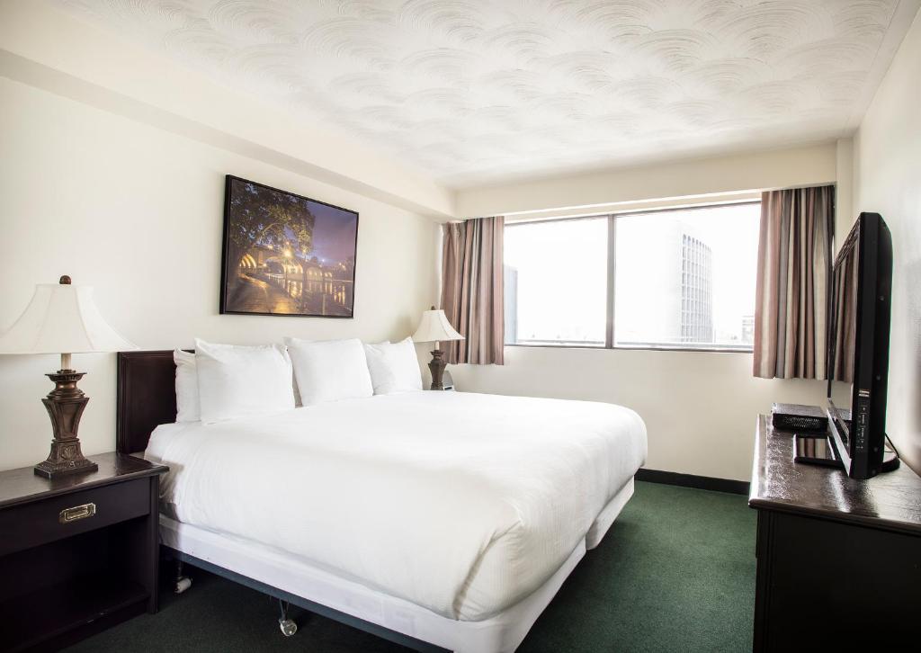 a hotel room with a large white bed and a window at The Business Inn in Ottawa
