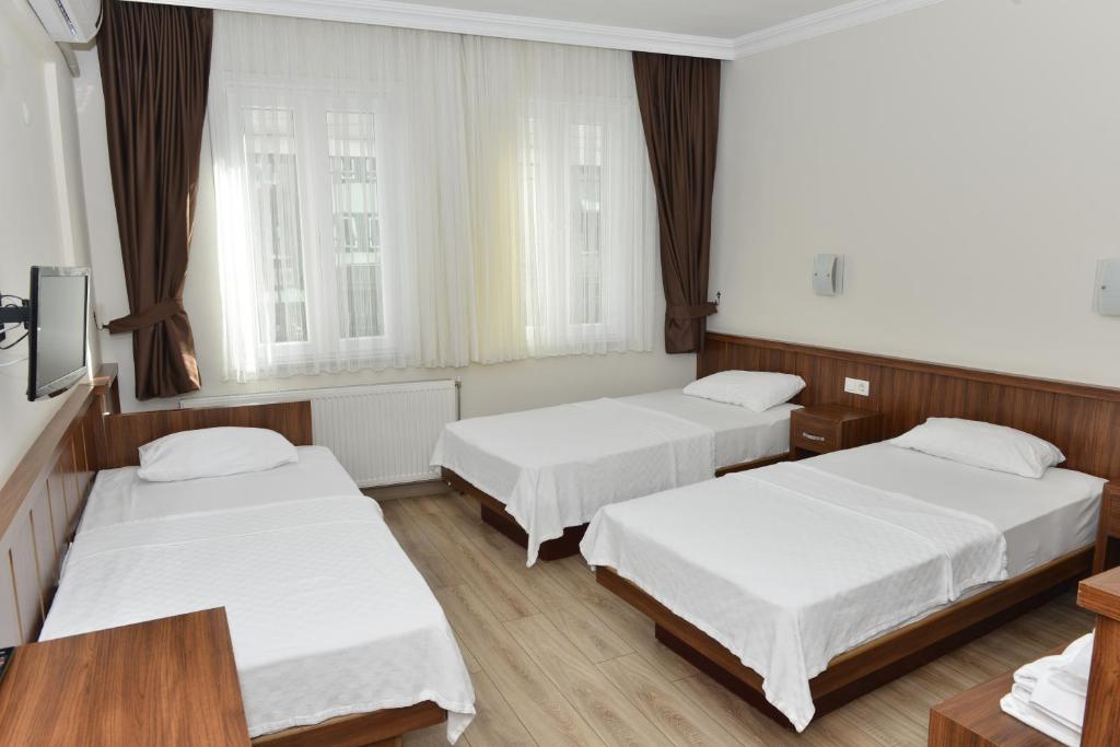 a hotel room with two beds and two windows at Bilgic Hotel in Kırklareli