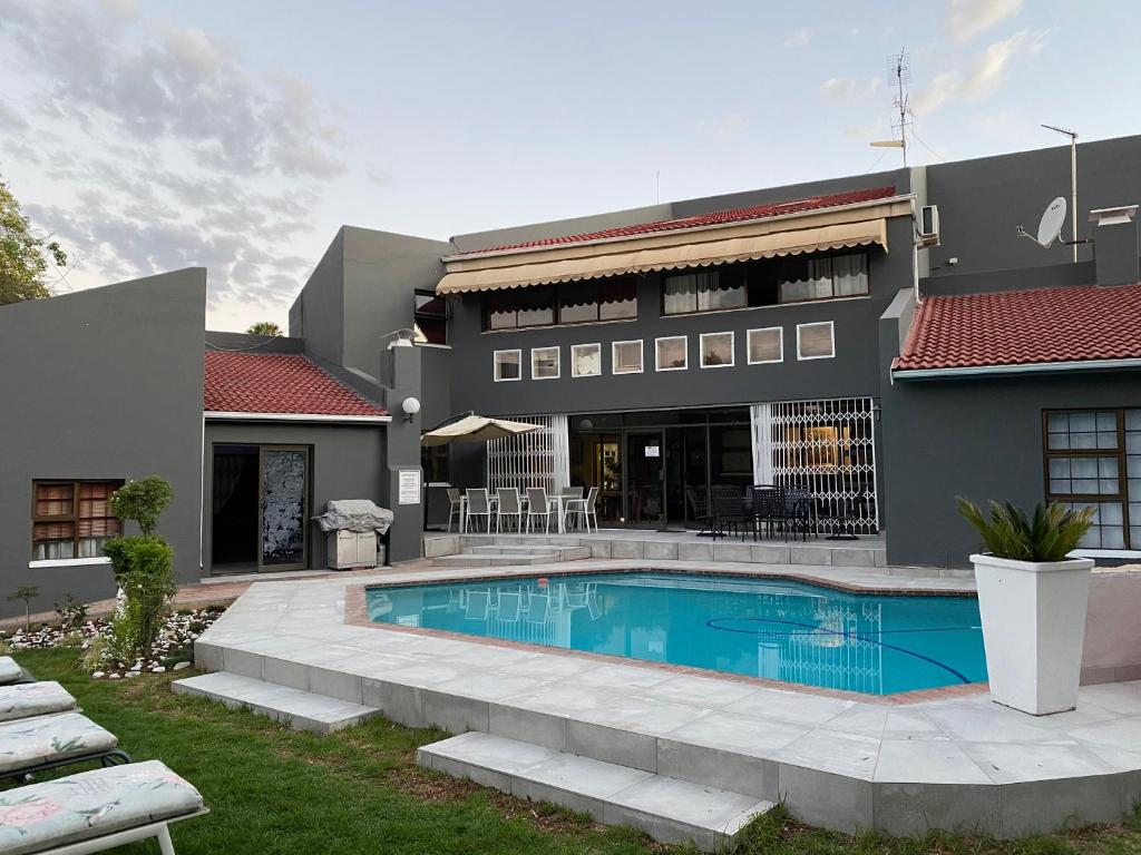 a house with a swimming pool in front of a building at Marion Lodge in Johannesburg