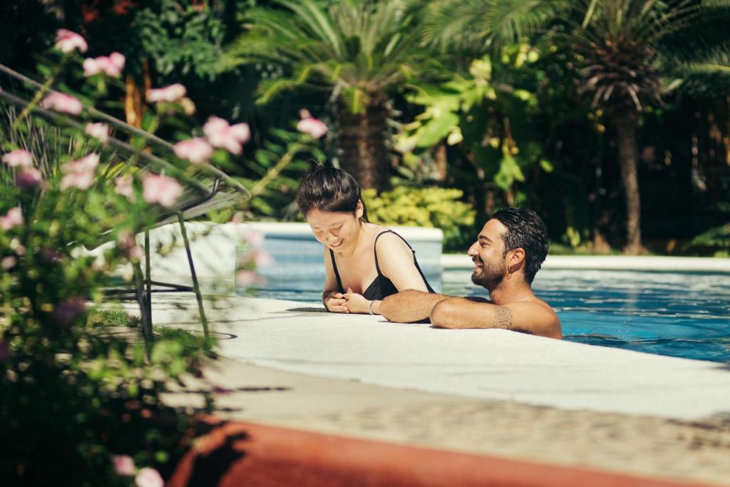 a man and a woman sitting in a swimming pool at Casa Losodeli & Coworking- Adults Only in Puerto Escondido