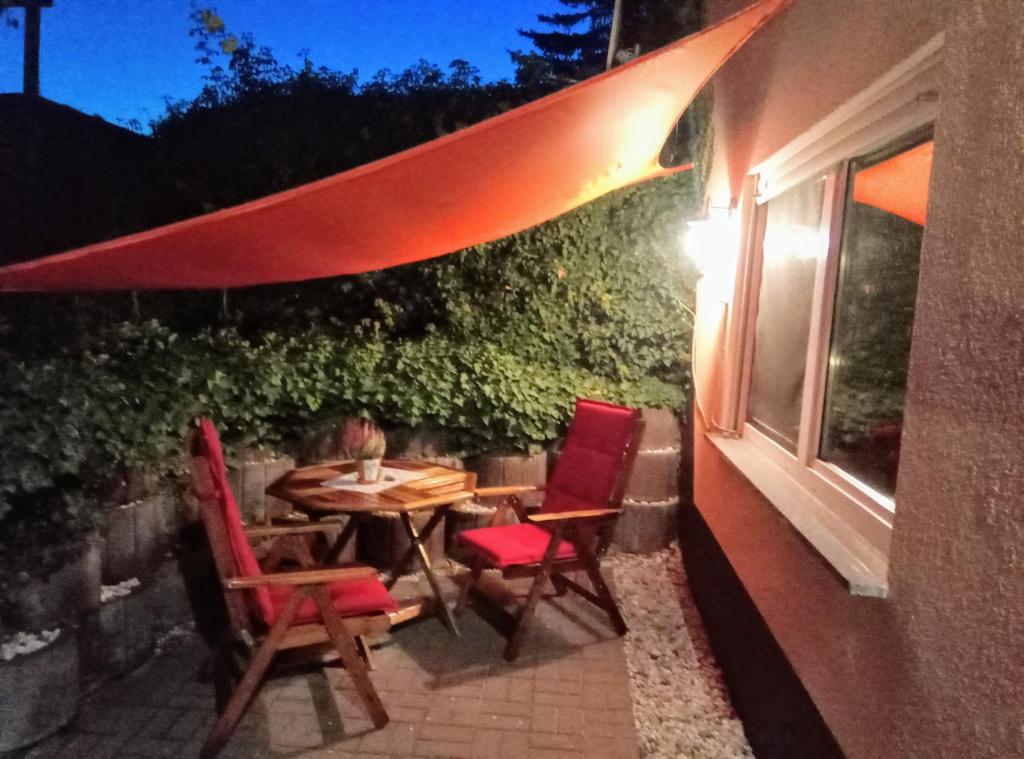 eine Terrasse mit einem Tisch, Stühlen und einem Fenster in der Unterkunft Pension "Am Zuckerberg" in Brahmenau