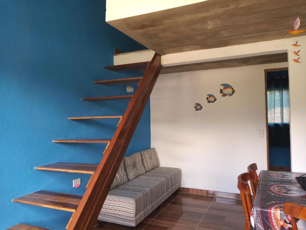 - un escalier en bois dans une chambre avec un canapé dans l'établissement Paraíso dos passaros - Chalé II Arara Azul, à Ilhabela