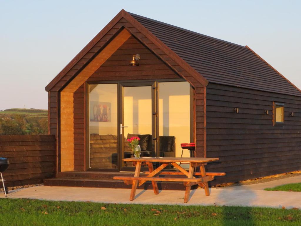 una pequeña cabaña con una mesa de picnic frente a ella en Islandcorr Farm Luxury Glamping Lodges and Self Catering Cottage, Giant's Causeway en Bushmills