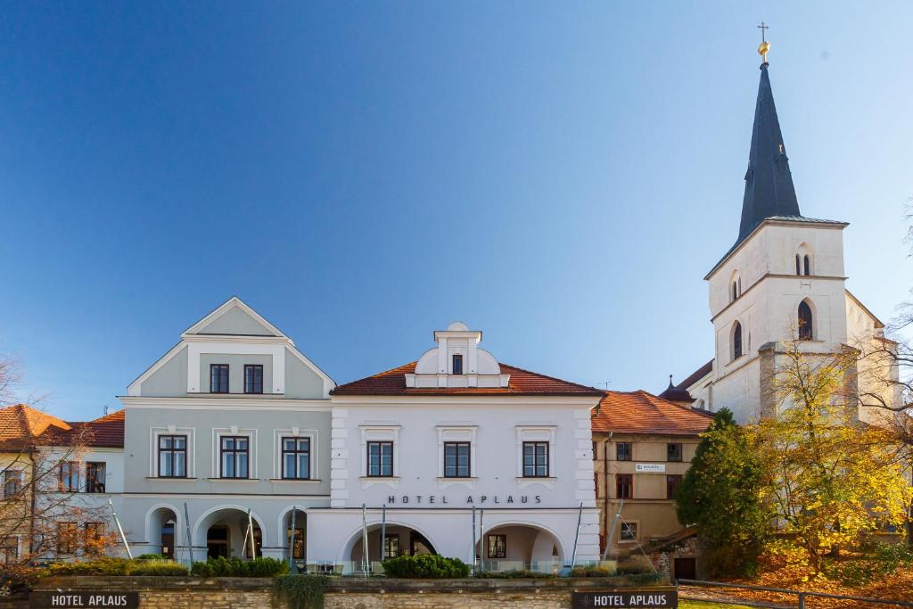 a white building with a steeple and a church at Hotel Aplaus in Litomyšl