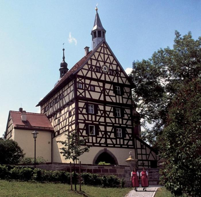 um grande edifício com pessoas de pé na frente dele em Turmstüble im Torhaus von 1545 em Burgbernheim