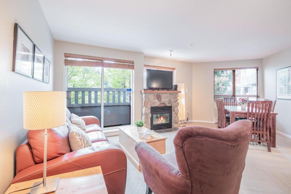 a living room with a couch and chairs and a fireplace at Deer Lodge by Outpost Whistler in Whistler