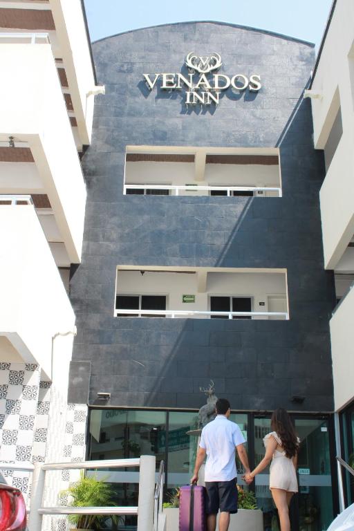 a man and woman holding hands in front of a building at Venados Inn in Mazatlán