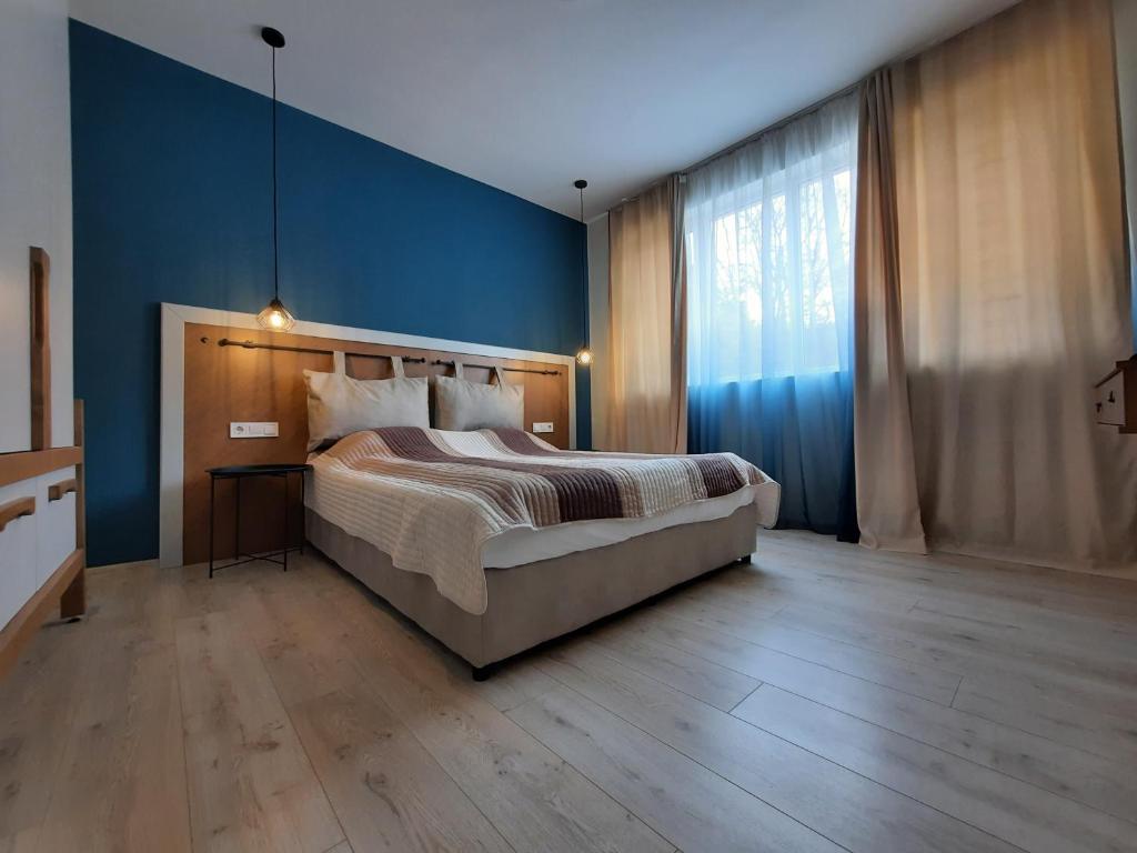 a bedroom with a large bed and a blue wall at Апартамент Тилия in Gabrovo