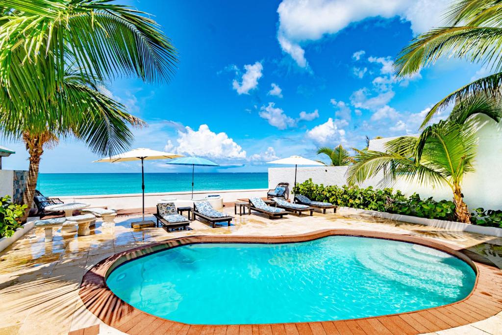 una piscina con sillas y sombrillas en una playa en Caprice 14 - Oceanfront Villa - Gated Community with Pool, en Nassau