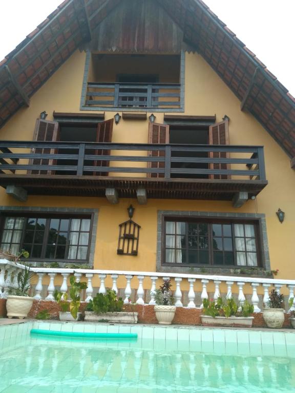 a house with a swimming pool in front of it at Casa com Piscina e Churrasqueira Perto da CBF, Feirarte, Parque Nacional in Teresópolis