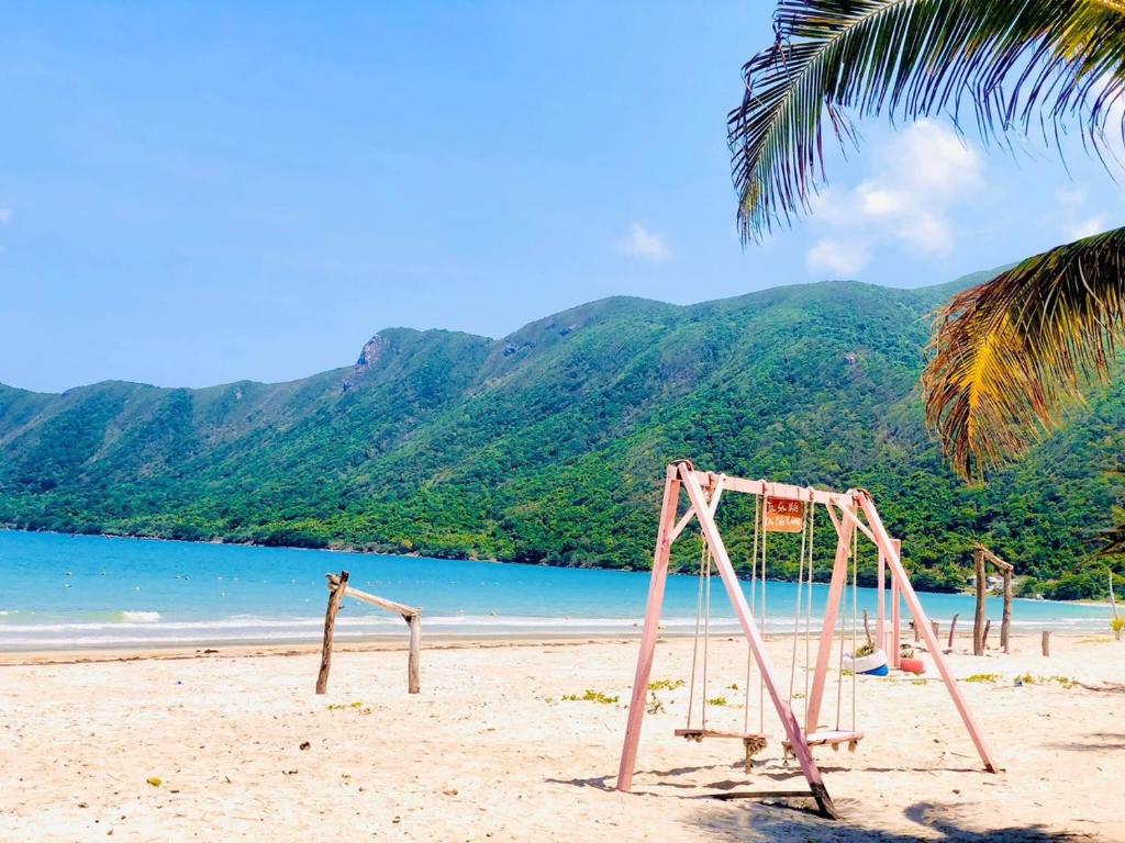 an empty swing set on a beach with a palm tree at Tan Son Nhat Con Dao Resort in Con Dao