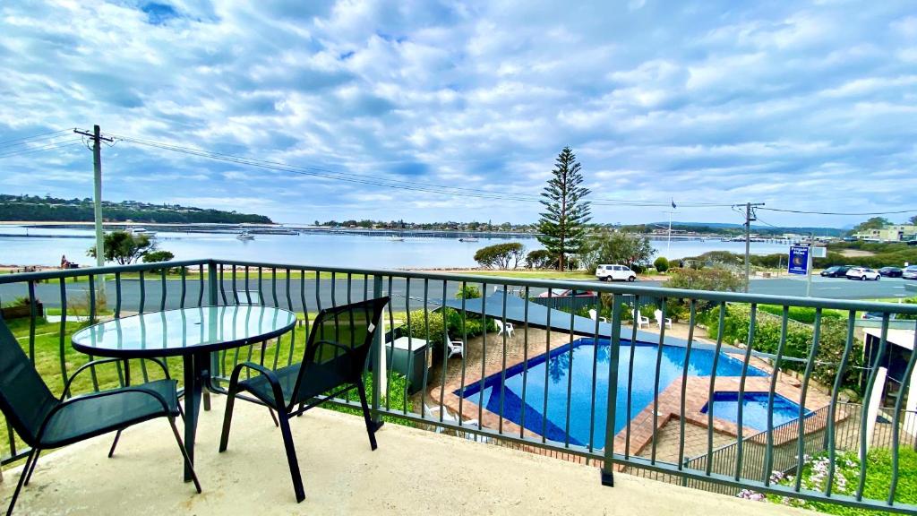 a balcony with a table and chairs and a swimming pool at Penguin Mews Merimbula in Merimbula
