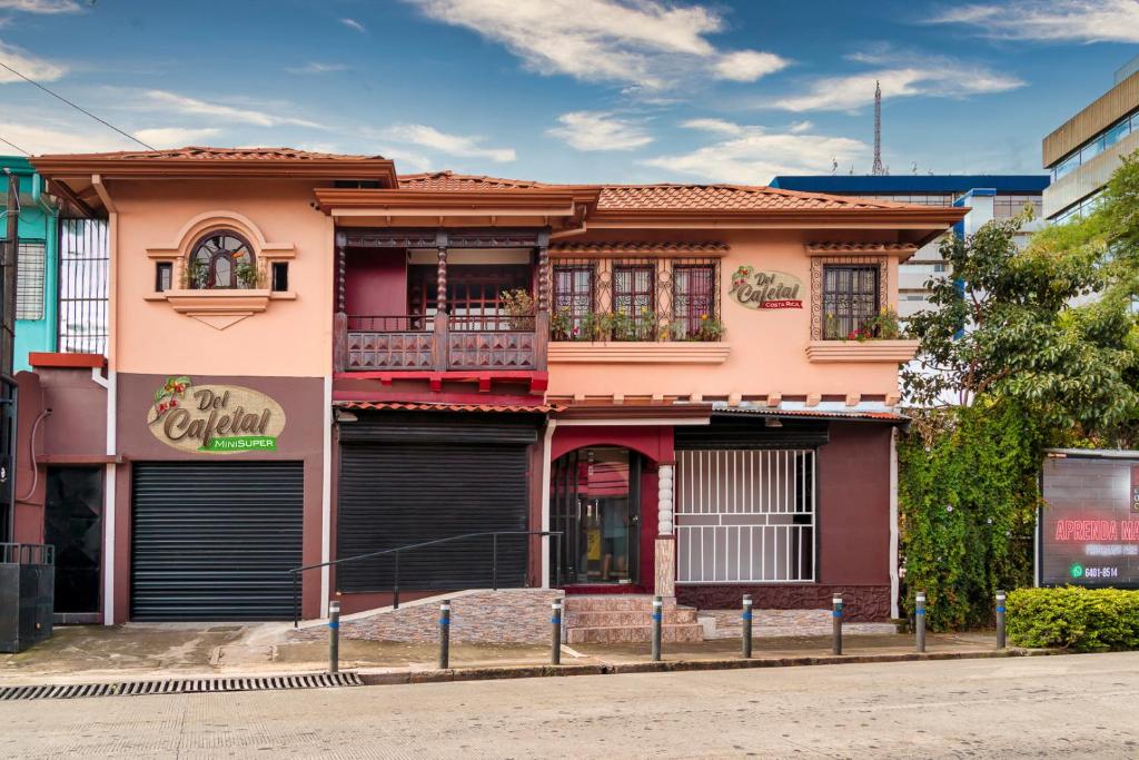 une maison rose avec un balcon dans une rue dans l'établissement Delcafetalcr, à San José