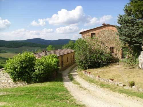 uma estrada de terra ao lado de um edifício numa colina em Borgo Carpineto em Vagliagli