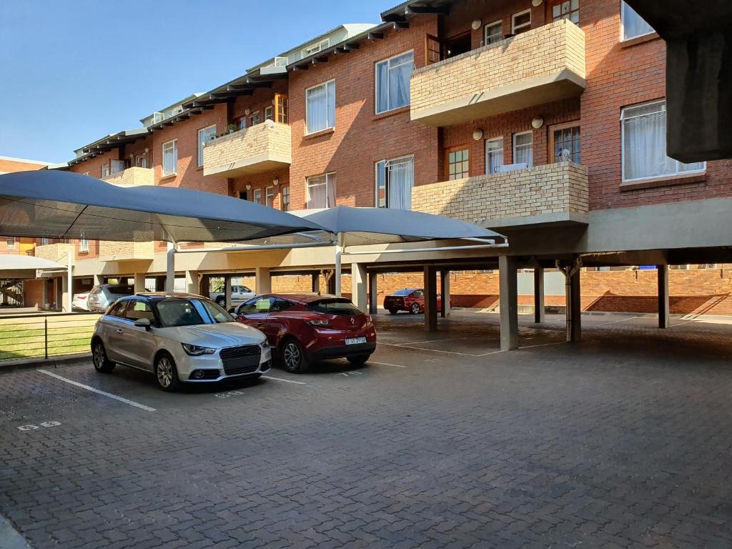 two cars parked in a parking lot in front of a building at Melville Mews-2- Auckland park in Johannesburg
