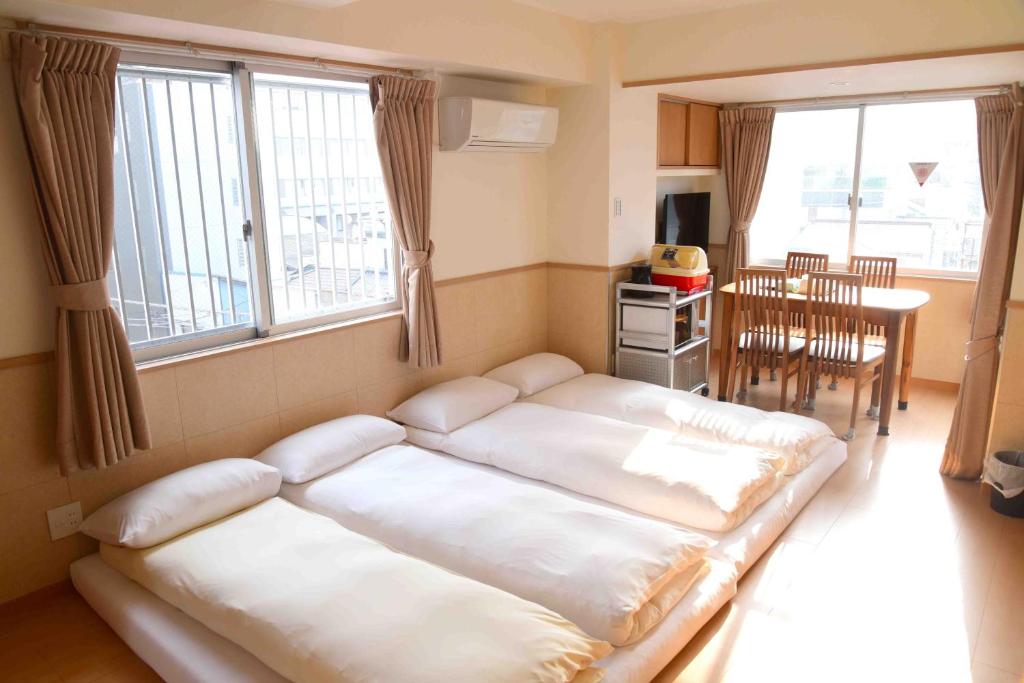 Zimmer mit 2 Betten in einem Zimmer mit einem Tisch in der Unterkunft 上野之家分館家庭房 in Tokio