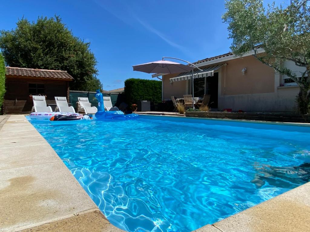 アレにあるMaison avec piscine chauffée Bassin d Arcachonの青い大型スイミングプール(椅子、パラソル付)