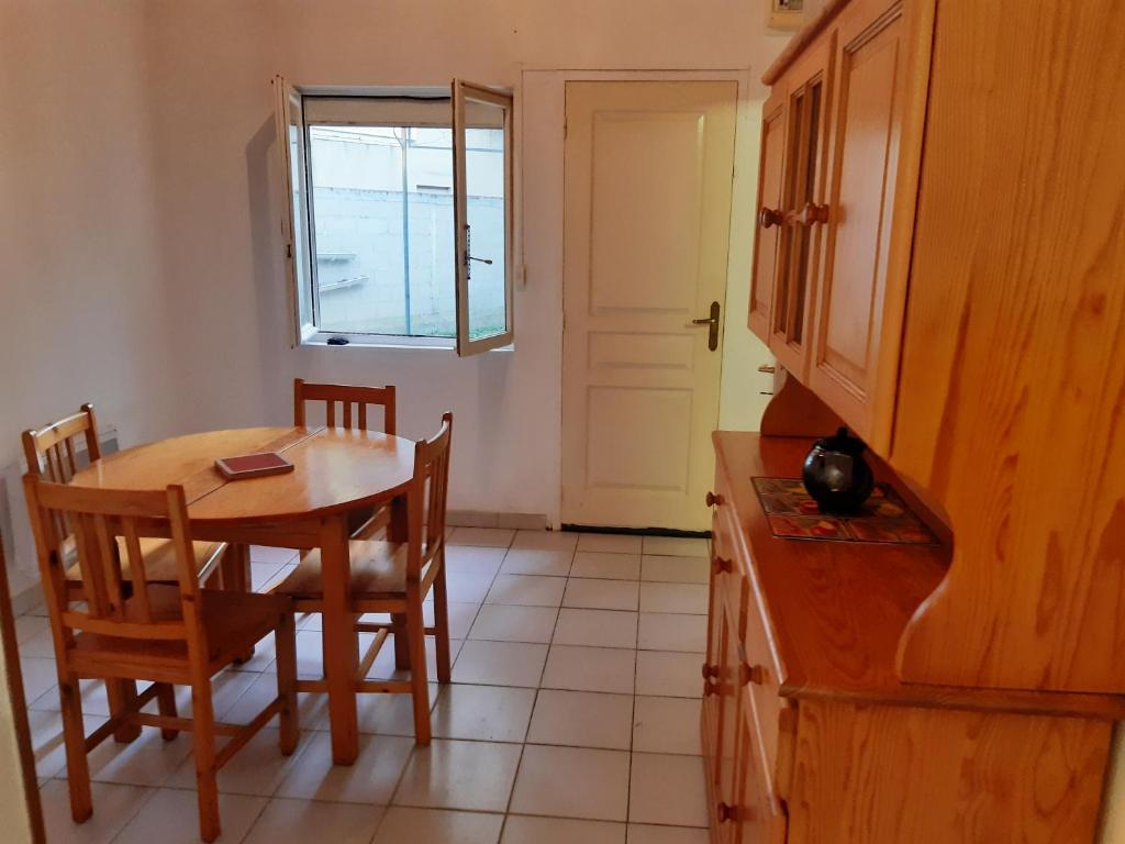 eine Küche mit einem Tisch, Stühlen und einer Tür in der Unterkunft L'escale du voyageur in Saint-Gaudens