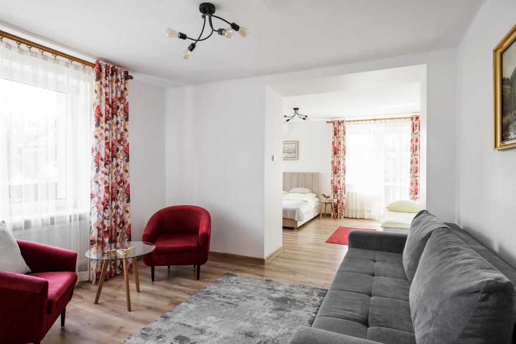 a living room with a gray couch and red chairs at Karina in Wisła