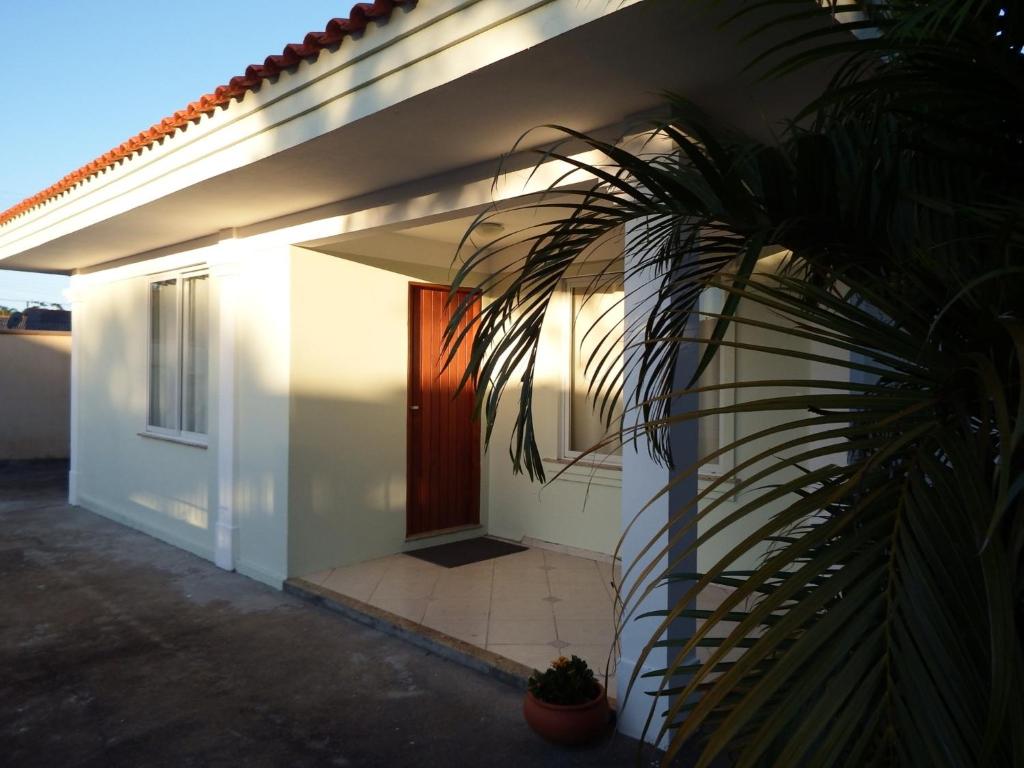 una casa blanca con una puerta y una palmera en Estúdio Labrador do Canal, en Florianópolis