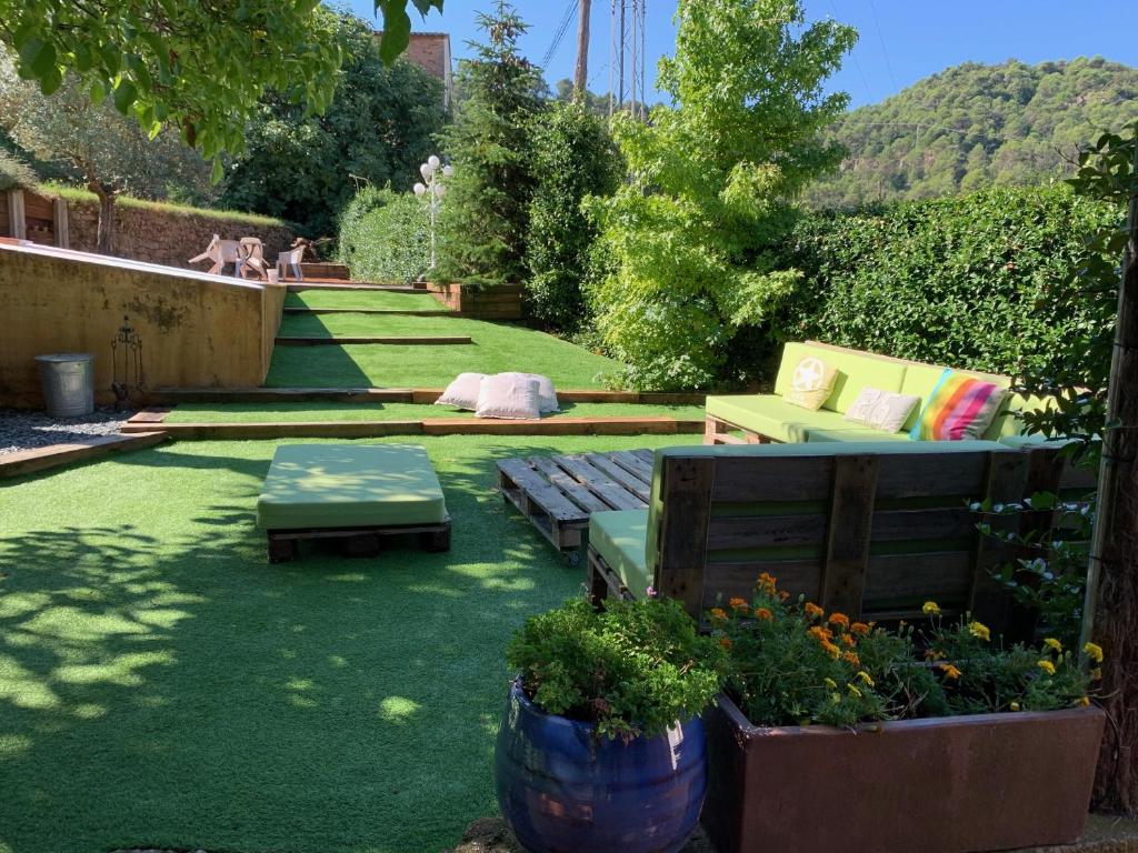 a backyard with a lawn with benches and plants at Cal Secretari in Rellinars