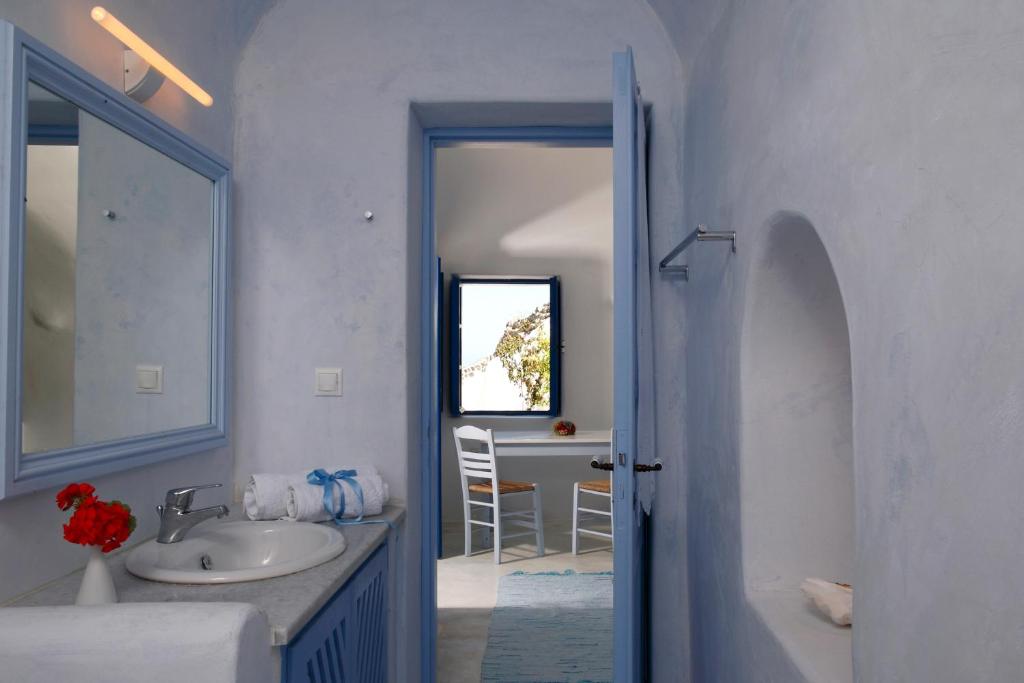 a white bathroom with a sink and a mirror at Aghios Artemios Traditional Houses in Imerovigli