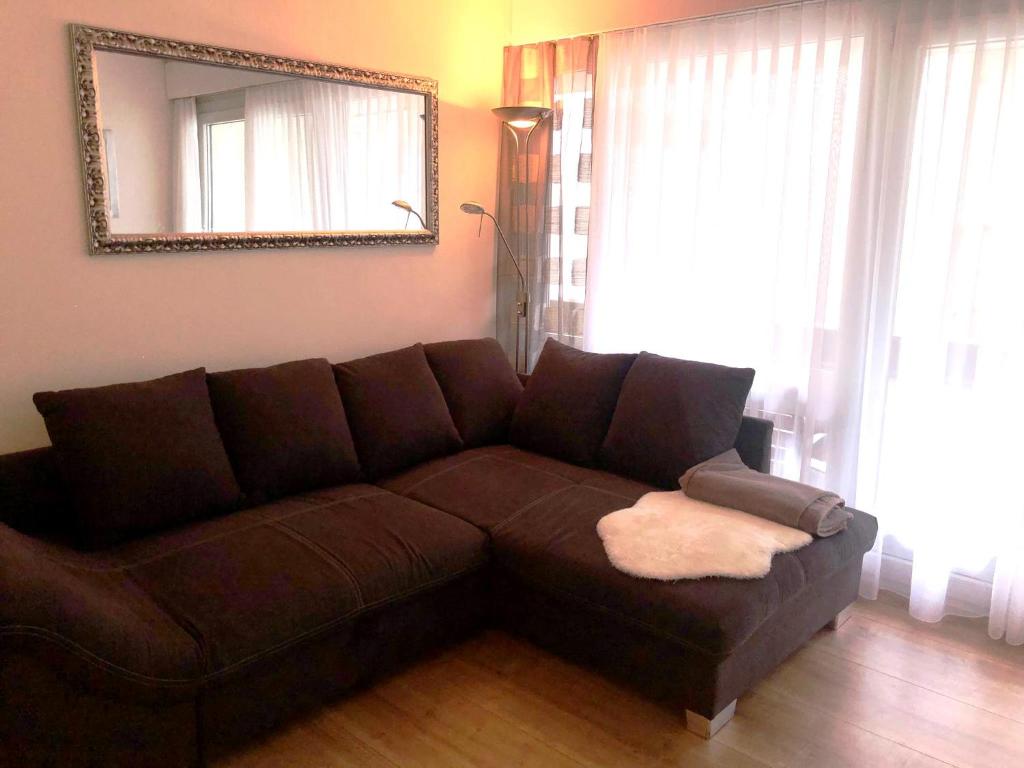 - un canapé brun dans le salon avec un miroir dans l'établissement Fortuna, à Loèche-les-Bains