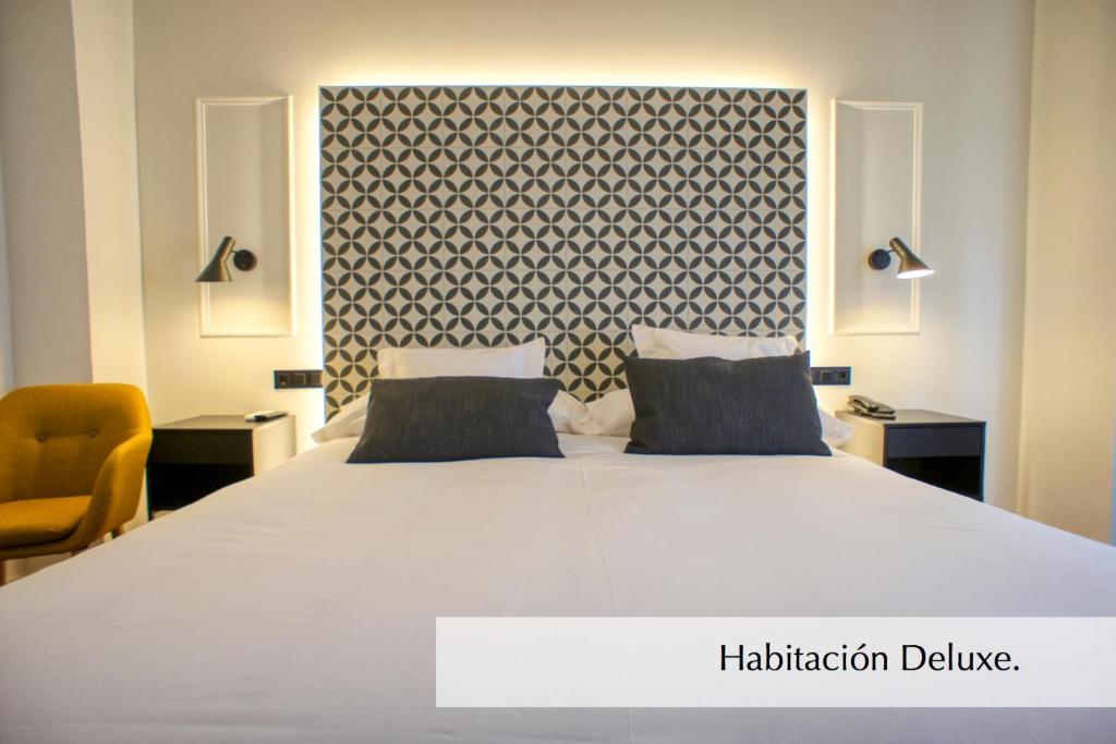 a bed with a white comforter and white pillows at Hotel Montermoso in Aranda de Duero