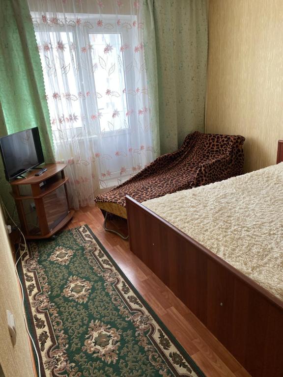 クルスクにあるApartments on prospekt Vyacheslav Klykova 80のベッドルーム1室(ベッド2台、テレビ、ラグ付)