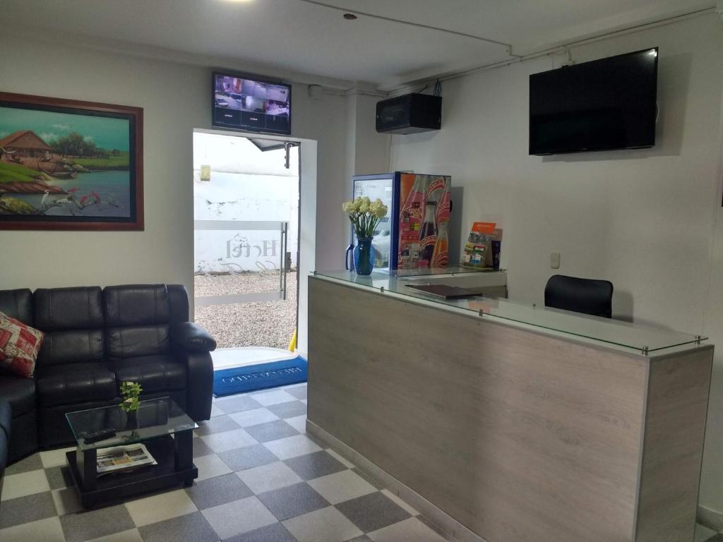 een lobby met een bar met een bank en een televisie bij HOTEL LA FONTANA in Yopal